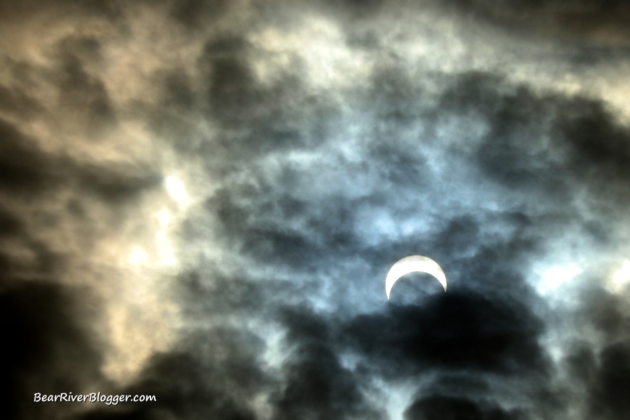 a partial solar eclipse peaking through the clouds on the bear river migratory bird refuge