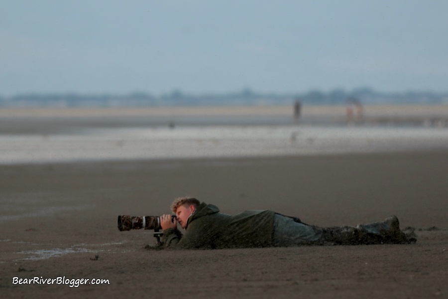 photographer laying on the ground photographing a sunset on the Great Salt Lake.